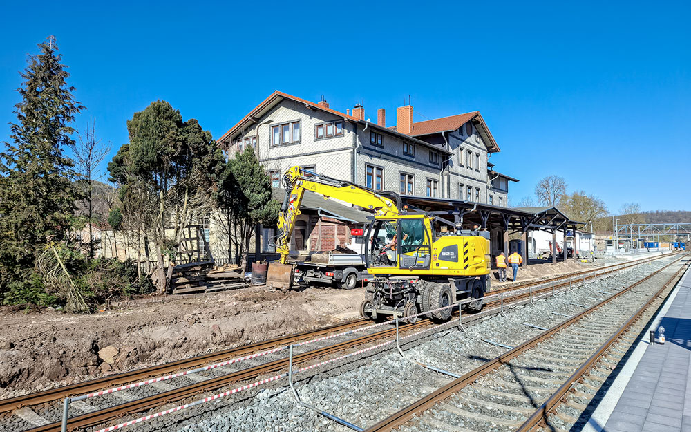 Ansicht des Bahnhofes von der Schienen her. Bild zeigt das Bahnhofsgebäude und die die Arbeiten am Gleisbett.
